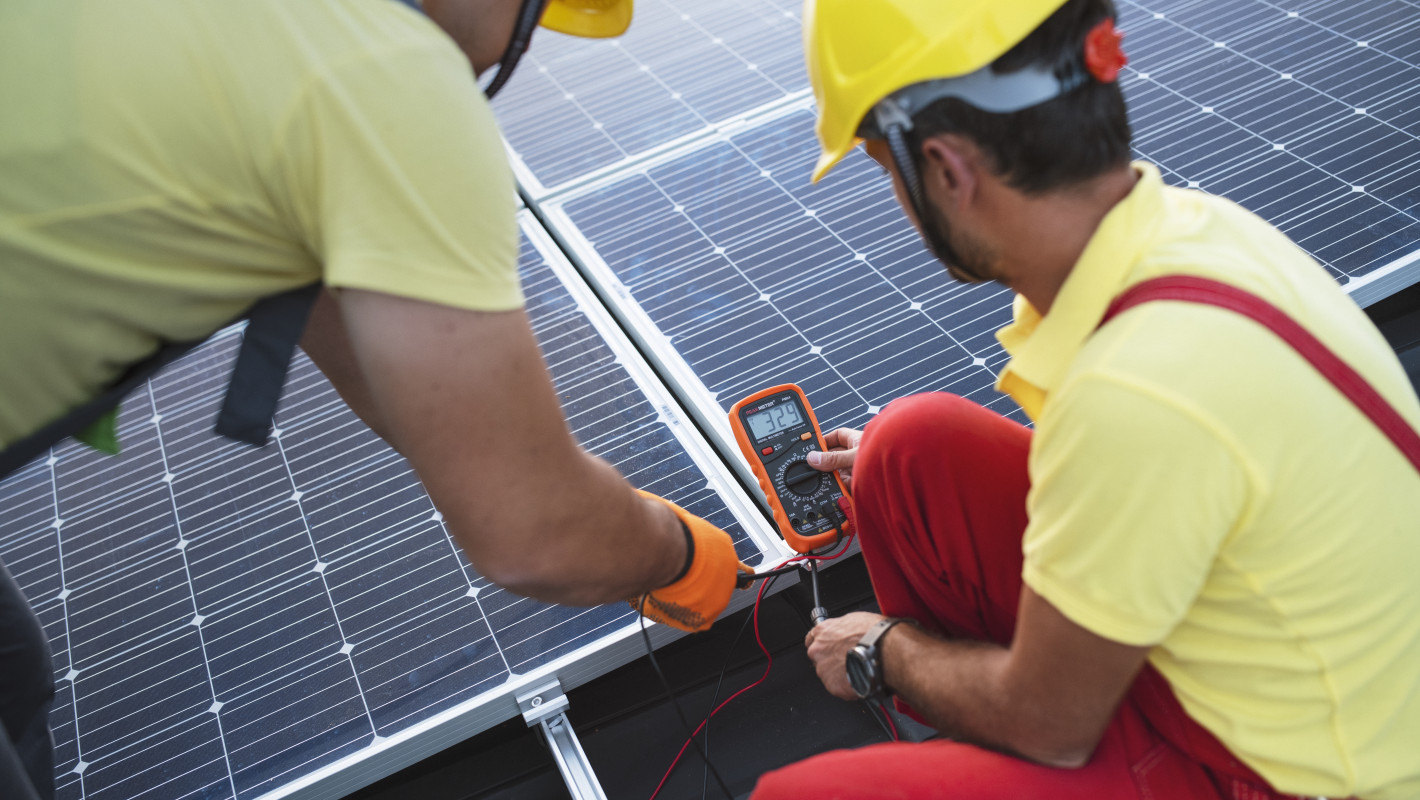 2 Arbeiter messen Strom an einer Solarzelle