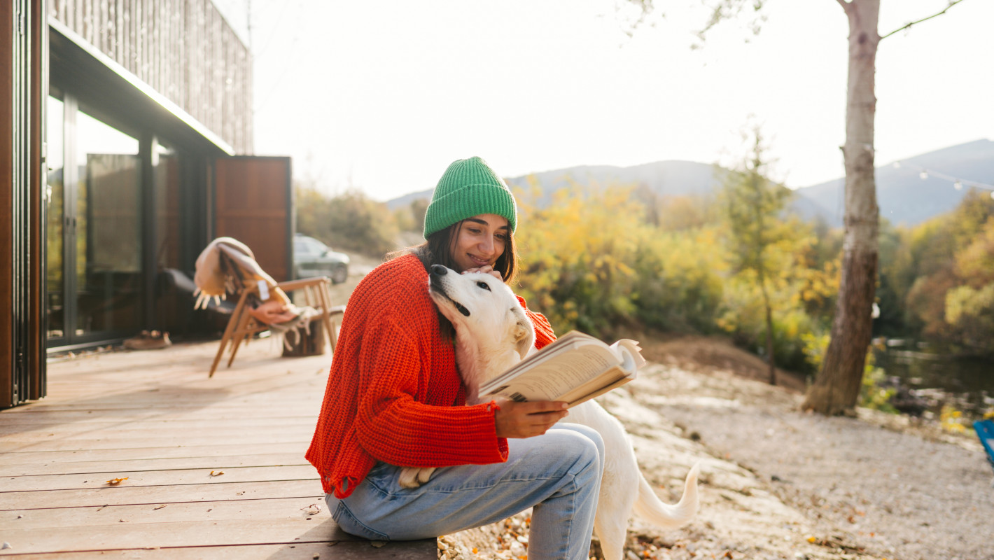 Frau liest ein Buch mit ihrem Hund