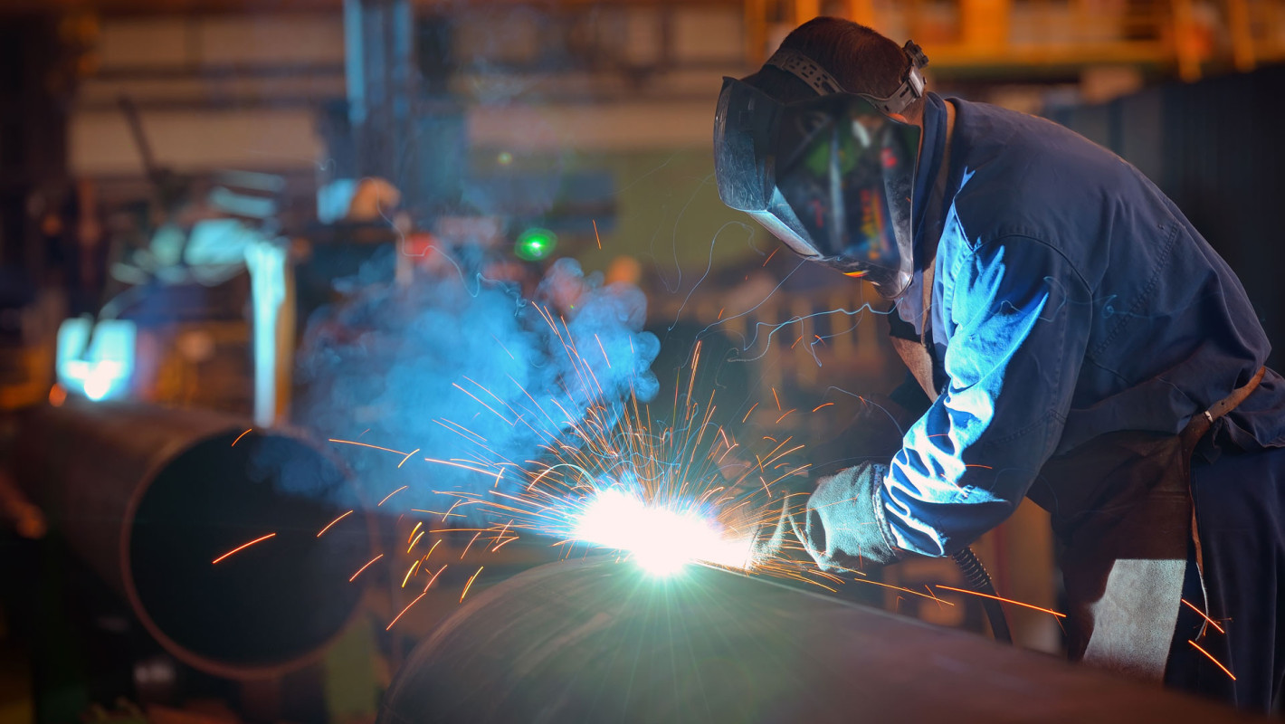 Mann arbeitet in einer Fabrik an Metall