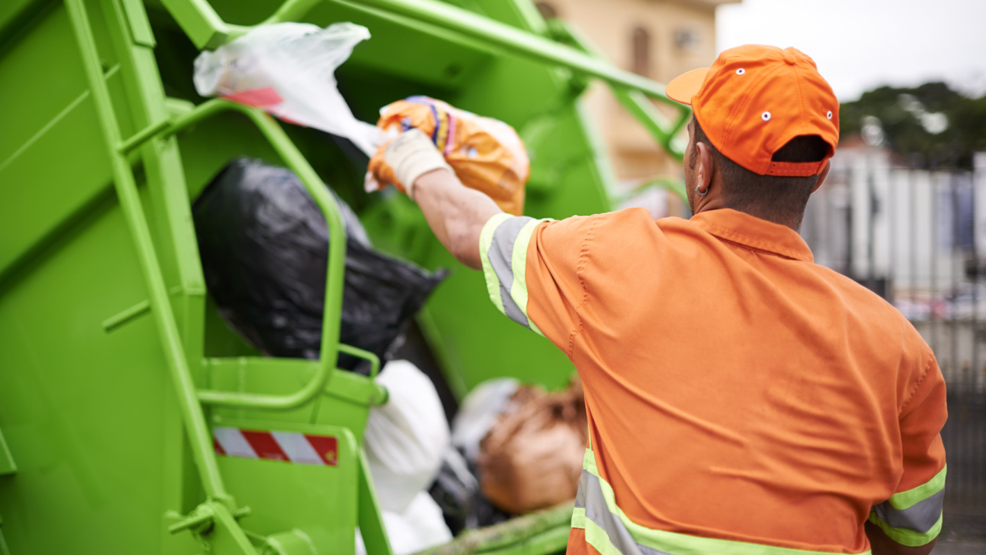 Müllmann wirft Mülltüten in den Müllwagen