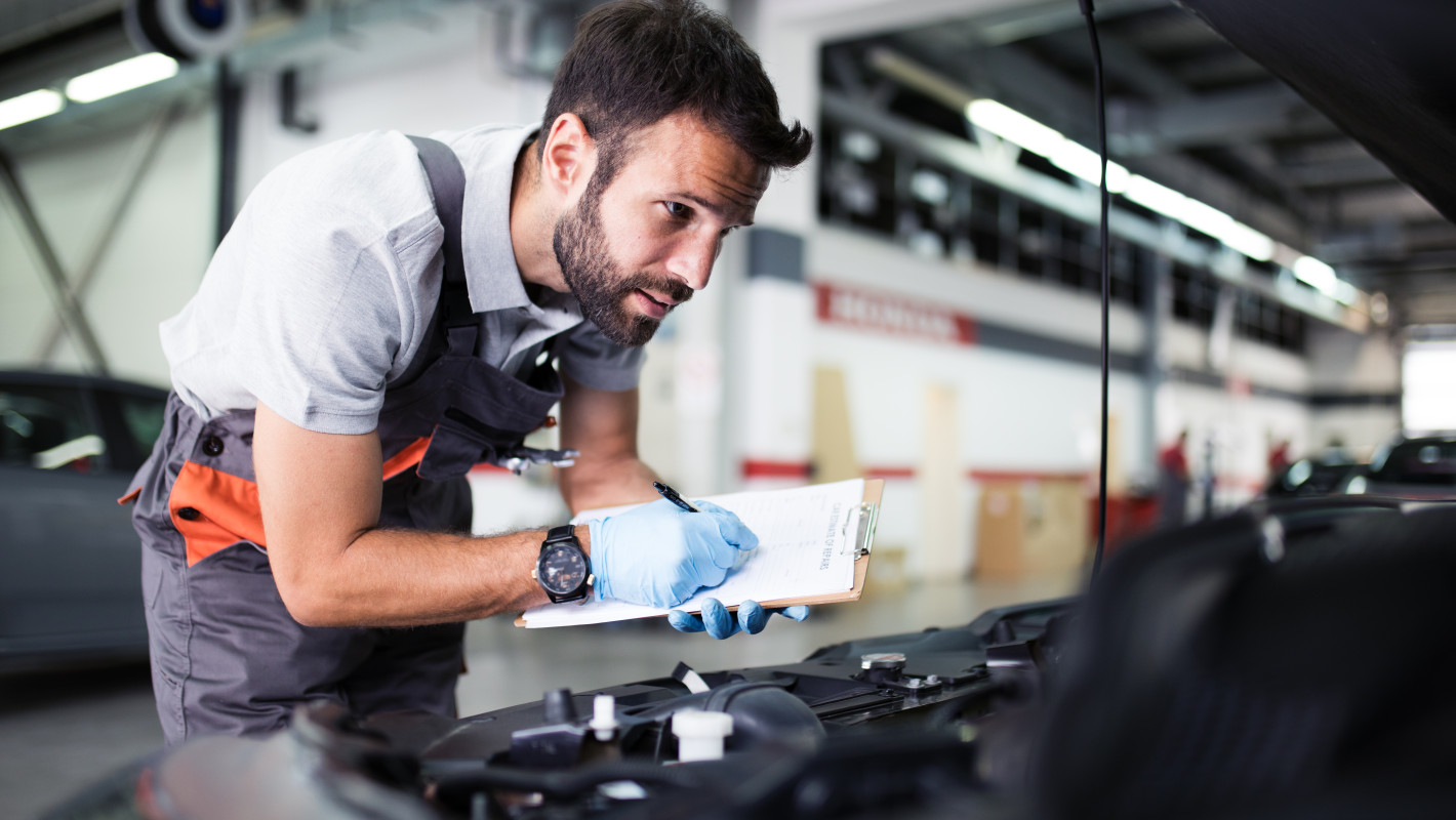 Arbeiter kontrolliert den Motor an einem Auto