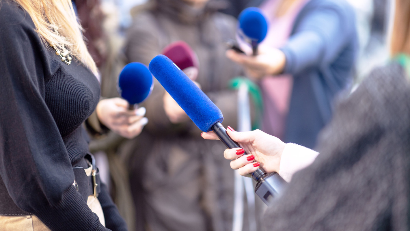 Journalisten mit Mikrofonen bei einer Pressekonferenz