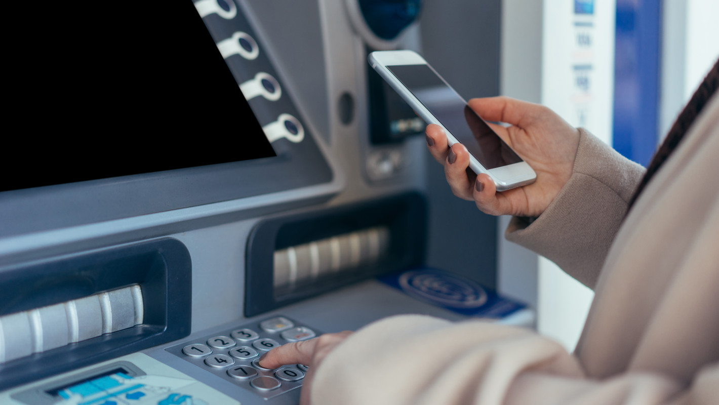 Frau hebt Geld ab mit Smartphone