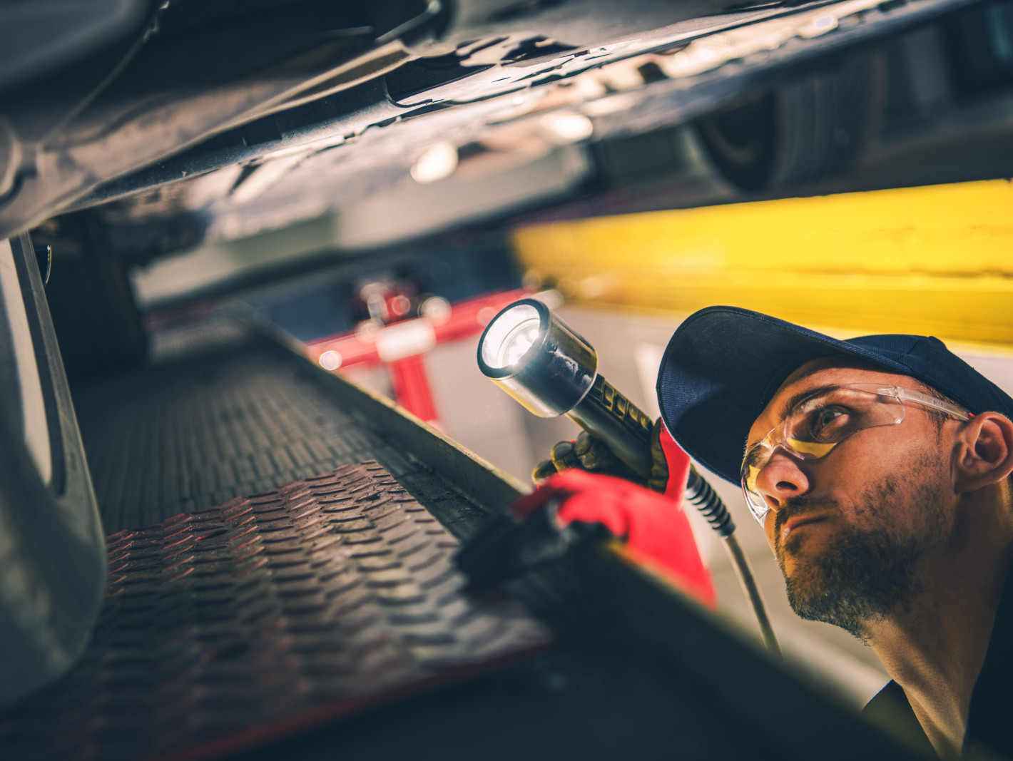 Automechaniker prüft ein Auto von unten