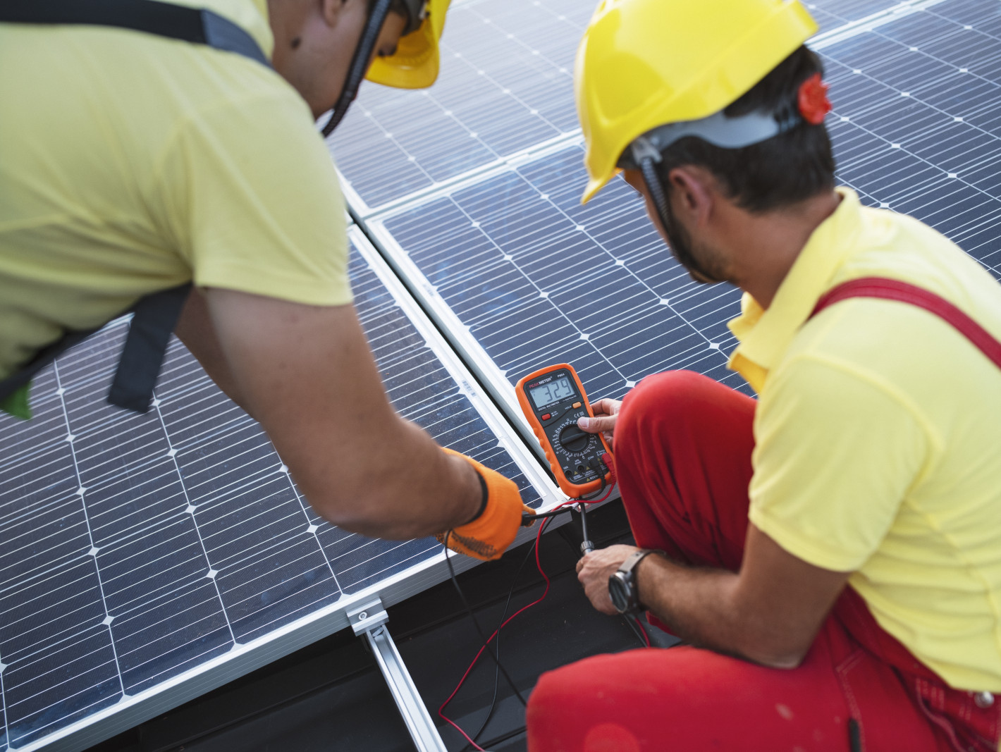 2 Arbeiter messen Strom an einer Solarzelle