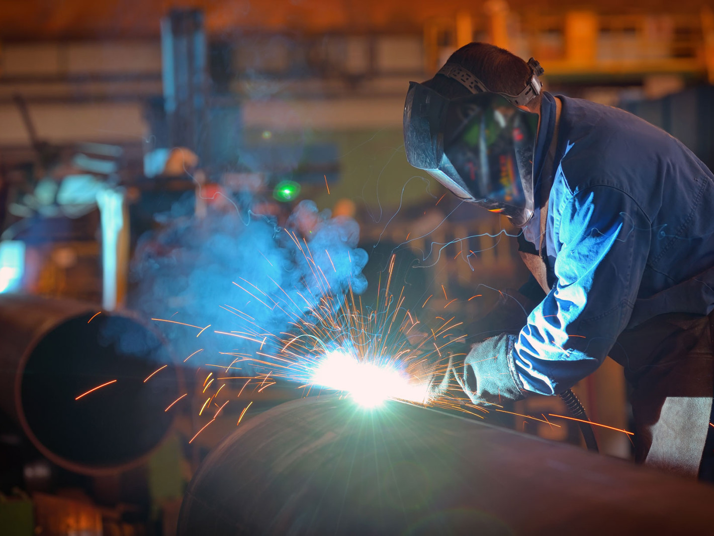 Mann arbeitet in einer Fabrik an Metall