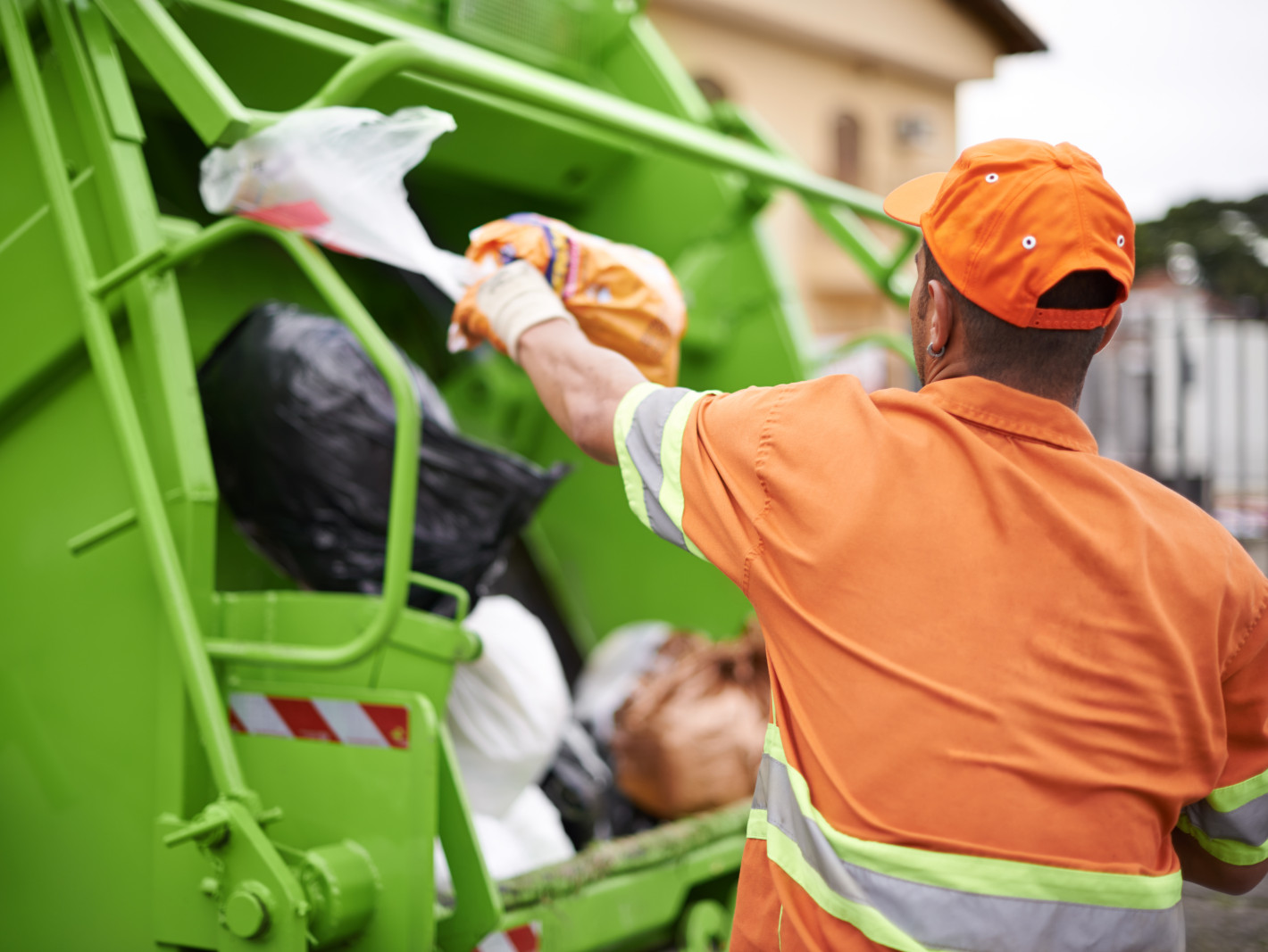Müllmann wirft Mülltüten in den Müllwagen