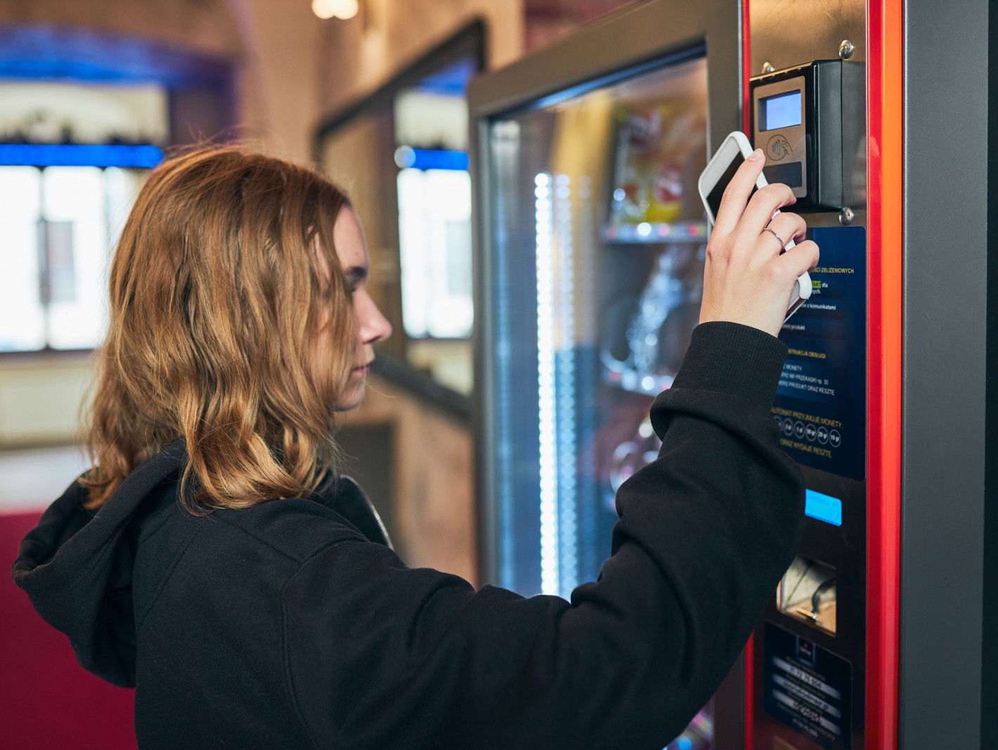 Mädchen bezahlt mit ihrem Smartphone an einem Automaten